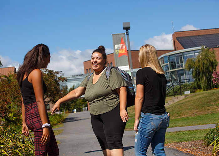 Three students talking outside on campus