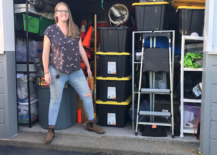 Liz Carr standing in front of an open garage filled with set items for a TV show.