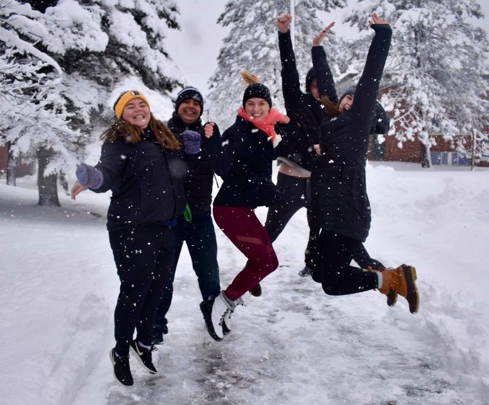 Students jumping for joy in a snow storym
