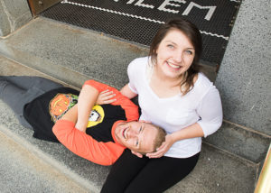 A man rests his head on a woman's lap, both smiling, looking at camera.