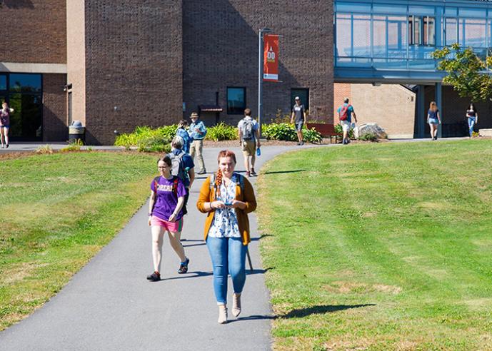 Students walking along a path, outside a college campus building.