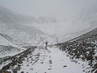 A person standing in a very rocky and snowy terrain.