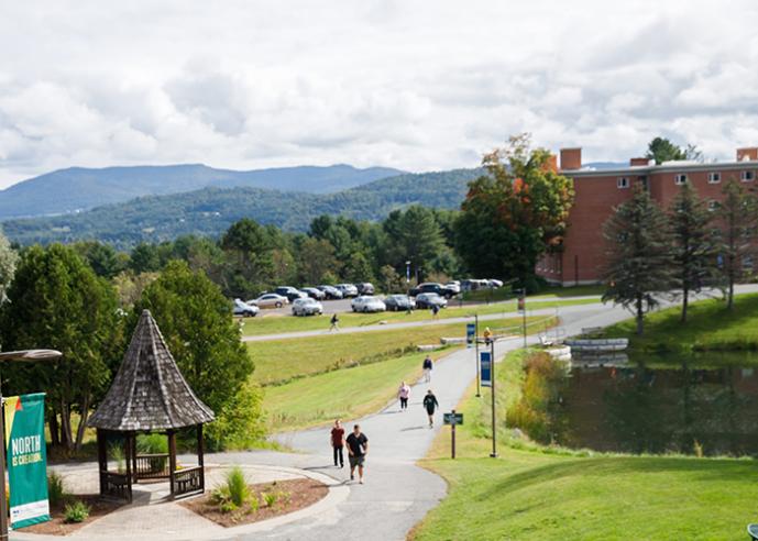 Students walking on a path at a college campus, trees and mountains in background.