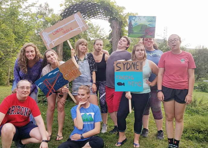 A group of students making funny faces and holding cardboard signs.