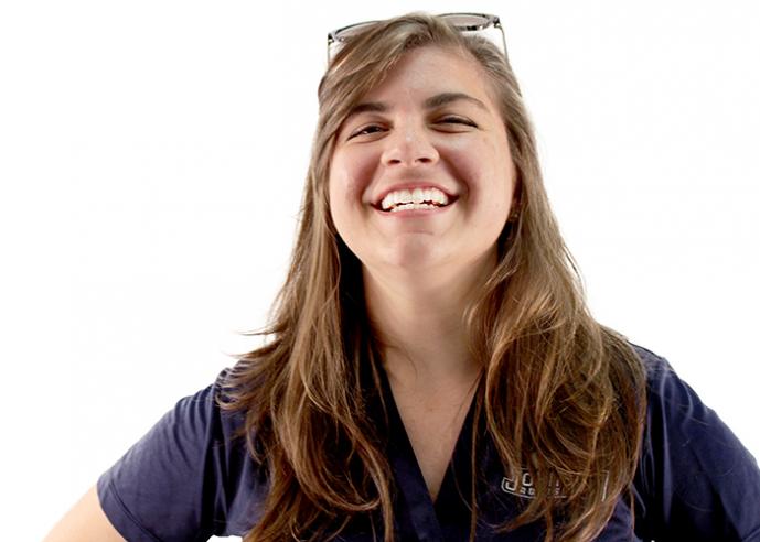 A woman with long hair and glasses on top of her head, smiles at the camera.