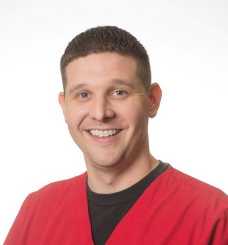 A man with short, brown hair, wearing a red shirt, smiling, looking at camera with white a background.