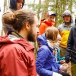 A group of students dressed for cold weather attend class outdoors.