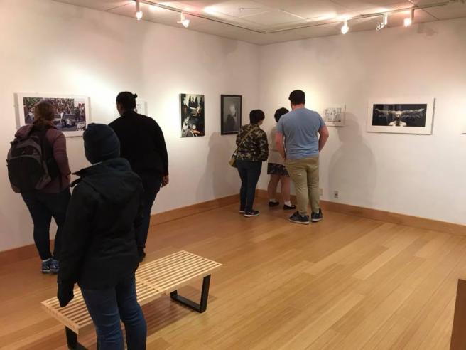 People look at black and white photographs in an art gallery.