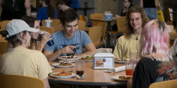 Students eating lunch at a table in a cafeteria.