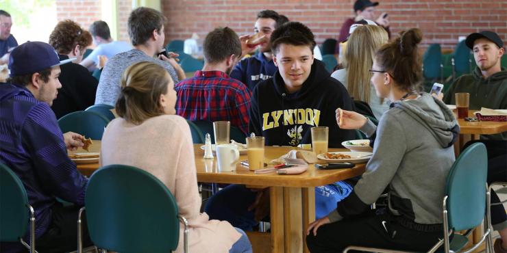 Students eating lunch at a table in a cafeteria.