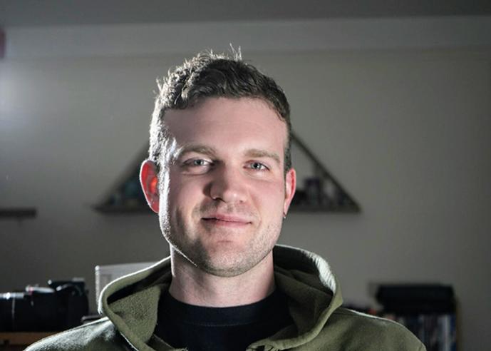 A man with brown hair, smiling, looking into the camera.