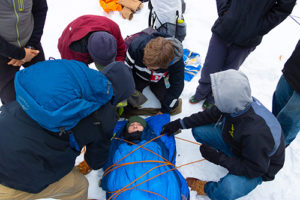 Student laying on a makeshift stretcher outside in the snow during a classroom exercise.