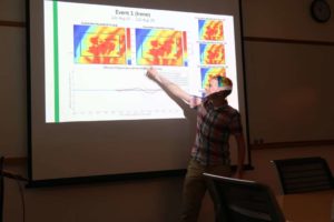 Student points at weather maps on a projector screen.