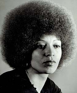 A woman with an afro in a black shirt stares sadly to the side of the camera.