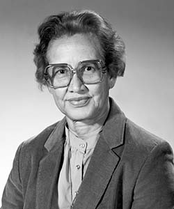 A portrait of a black woman with short curly hair and large glasses smiling at the camera.